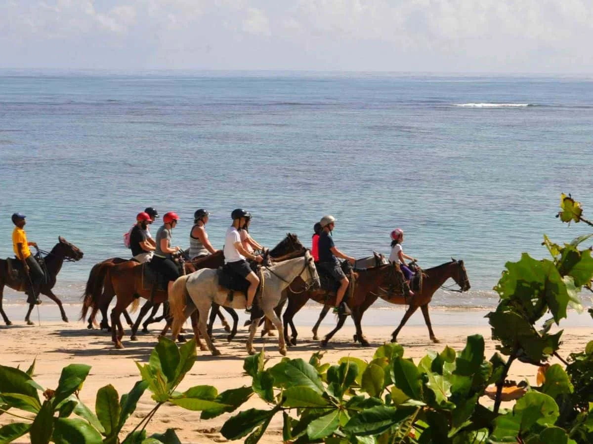 Pareja cabalgando por la orilla del mar Caribe al atardecer en Punta Cana