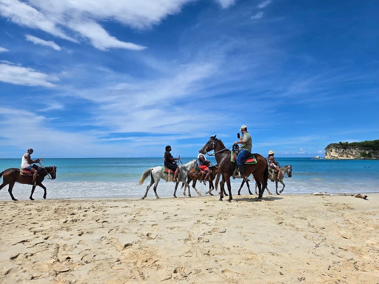 Grupo de jinetes cabalgando por una playa apartada en Punta Cana al amanecer